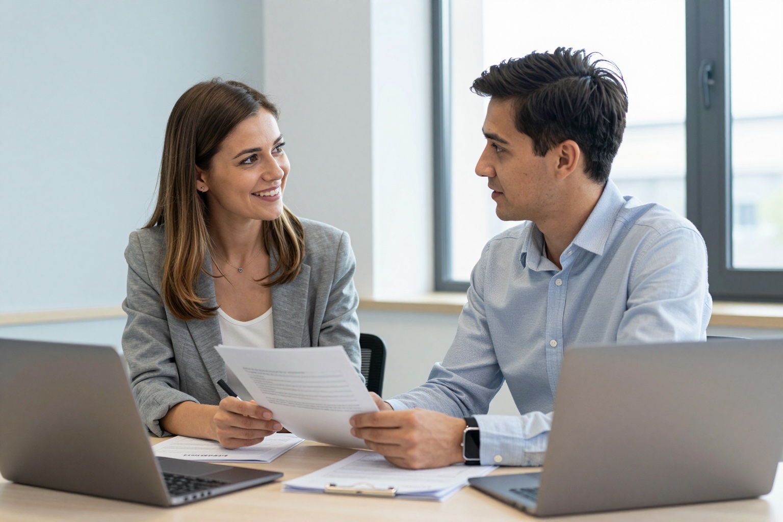 Beraterin und Arbeitssuchender im Gespräch mit Unterlagen und Laptop in einem Büro der Agentur für Arbeit